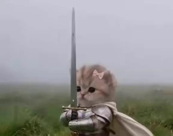 A cute kitten dressed in knight's armor with a pink bow holds a large sword upright in a grassy field.