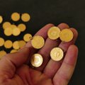 A hand holds up several gold coins with Turkish Lira symbols against a background of more coins. The image illustrates the post's discussion about gold's price peaking at 6,900 TL, which the author argues is not a true high but rather a final rally, given gold's underperformance compared to the BIST100 and US stock indices over the past five years.