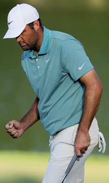 Scottie Scheffler, wearing a white Nike cap and a teal Nike polo shirt, pumps his fist in celebration on the golf course as he ties the lead at the FedEx St. Jude Championship in Memphis after surging to 6-under par through seven holes.