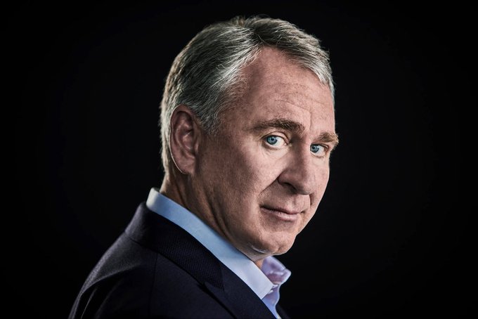 A distinguished older man with gray hair and striking blue eyes poses against a black backdrop in a professional portrait, wearing a dark suit jacket over a light blue collared shirt. His confident, slight smile conveys an authoritative presence fitting for a business or financial figure, aligning with the post's reference to "$55 $HYPE."