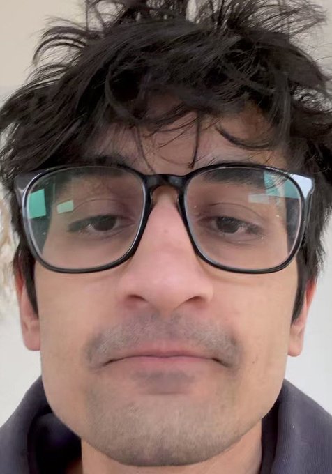 A close-up selfie of a man with messy dark hair and large black-framed glasses, with visible reflections of a screen in his lenses. The image relates to the post, likely showing the trader "frankdegods" celebrating or reacting to his profitable long position on UNI.
