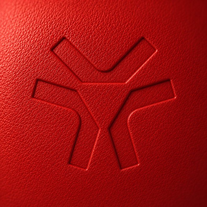 The image features a close-up view of a red surface with a logo prominently displayed, which appears to be a stylized triangle or an X shape. The background color of the image is red, providing contrast to the logo. The text "x.com/solana/status" can also be seen in the image, suggesting that this logo might be associated with a website or social media platform related to cryptocurrencies like Bitcoin.