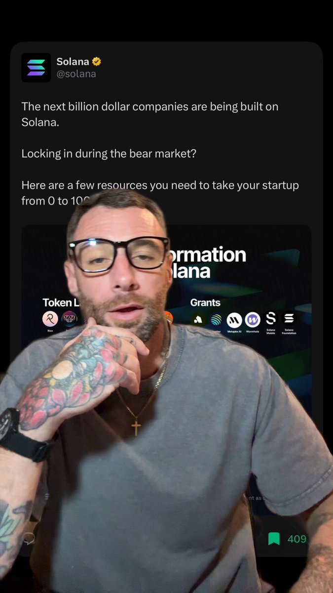 The image shows a man wearing glasses, with tattoos visible on his arm, posing for a photo or video call. He has a grey shirt on and appears to be talking about building Solana companies. The caption of the image reads "Just build on Solana it's that simple".