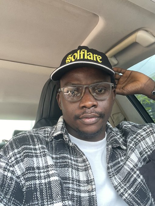 Selfie of a man wearing a 'Solflare' branded cap, glasses, and a plaid jacket, taken inside a car.