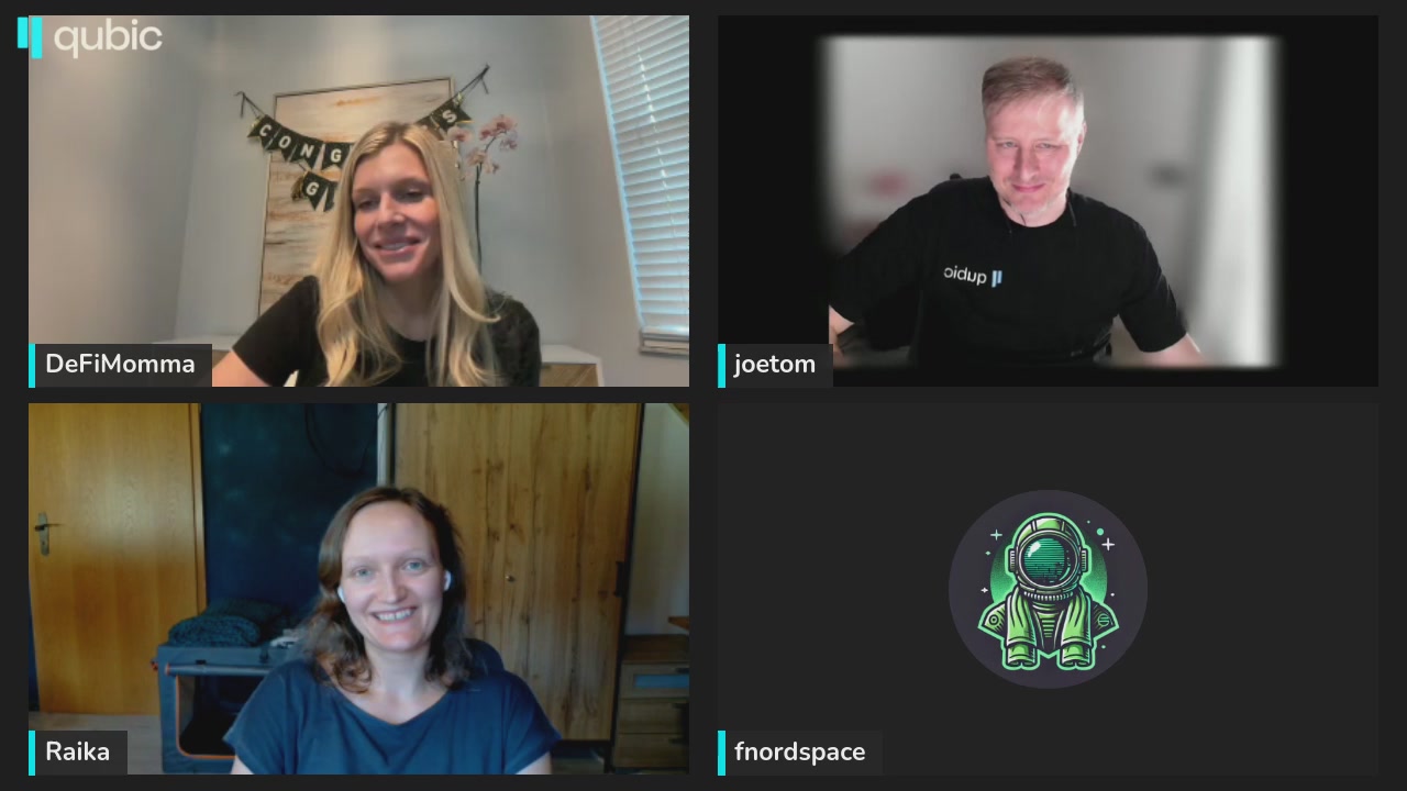 The image shows a computer screen with three people's faces, each sitting at their own desk. They are all smiling for the camera while engaged in an online meeting or video call using a platform like Zoom. The background of the image features a wooden wall, which adds a warm and homely touch to the setting.