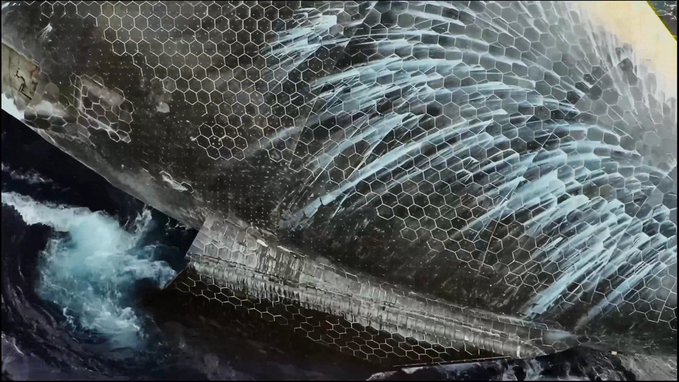 Textured artwork or mural featuring a hexagonal honeycomb pattern with flowing, wave-like brushstrokes in white, gray, and black tones.
