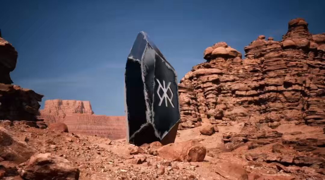 The image features a large rock formation with a black stone sitting atop it, surrounded by red rocks. The rock formation appears to be part of a desert landscape, possibly in a canyon or rocky area. In the background, there are mountains visible against the sky, adding depth and scale to the scene. The post accompanying this image provides information about the rock formation and its significance, likely related to the legend of King XCX.