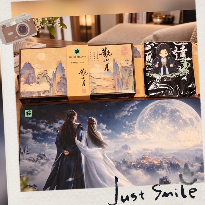 A promotional display of 'STRIKE FINANCE' branded merchandise featuring a 'Mid-Autumn Festival 2026' themed gift box with classical Chinese landscape art, a chibi character foil pack, and a large desk mat depicting two figures in traditional robes under a full moon, captioned 'Just Smile'.