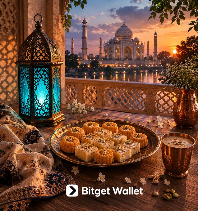 The image features an ornate table with a plate of food, including pastries and other treats, as well as a vase filled with flowers. The setting appears to be a dining area or a restaurant, possibly located near the Taj Mahal in India. A large blue lantern is also present on the table, adding to the ambiance. In the background, there are two buildings visible, one of which could be the Taj Mahal itself. The image includes text that reads "Eid Mubarak! Wishing you peace that never dips, joy that keeps pumping, and blessings so big they make your holdings look like a 100x moonshot!".