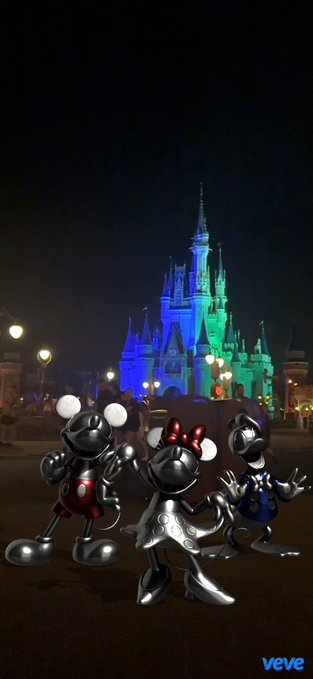Three silver Mickey Mouse figures stand in front of Cinderella Castle illuminated in blue and green at night, with the VeVe logo in the corner.