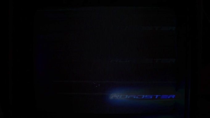 Very dark image showing the illuminated 'MONSTER' logo in blue/white light on what appears to be a computer case or device in low lighting.