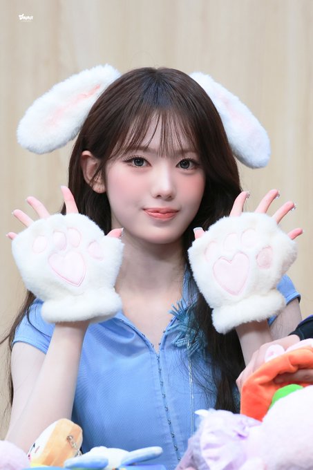 A young woman with long dark hair poses wearing fluffy white and pink bunny ears and matching paw gloves with heart-shaped pads. The post tags (#SUI #KiiiKiii #수이 #키키) and caption "이날완전토끼" (totally a bunny that day) align with her adorable rabbit-themed styling, suggesting this is a fan event or photoshoot appearance by KiiiKiii member Sui on August 28, 2025.