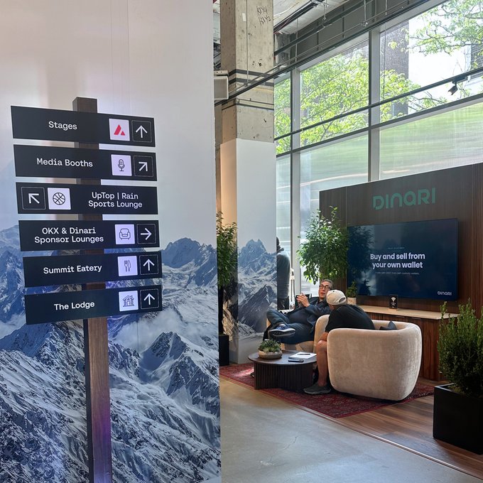 An event venue shows directional signs pointing to Stages, Media Booths, Summit Eatery, and other areas, alongside a Dinari booth where two people converse in a lounge setting.