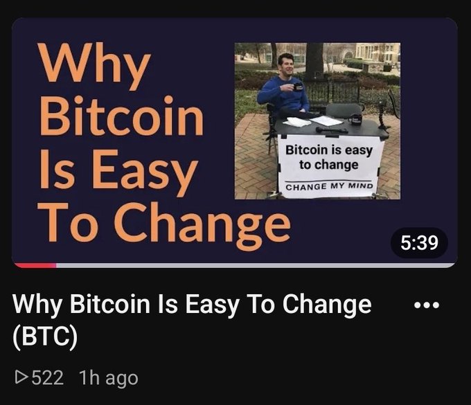 A YouTube thumbnail titled "Why Bitcoin Is Easy To Change" shows a man at a "Change My Mind" table with the sign "Bitcoin is easy to change," mocking the creator's claim after launching his own altcoin rather than successfully changing BTC itself. The 5:39 video, posted 1 hour ago with 522 views, appears to be a follow-up from a Bitcoin commentator who previously attempted to alter the protocol via BIP-110 but was rejected by the community, prompting him to create a new cryptocurrency instead.