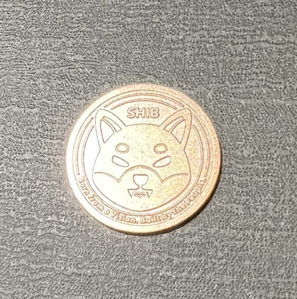 A commemorative coin featuring a Shiba Inu dog design with the text 'SHIB' and 'SHIBANO VISION' engraved on its face.