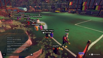 The image shows a group of people standing around a soccer field, with some players wearing red shirts and others wearing blue shirts. The scene appears to be from an online game or social media platform where users can interact with each other by tagging themselves in the game's chat box. A player is holding a soccer ball while another player has a backpack on their back. There are also several flags visible, possibly representing different teams or groups within the game.