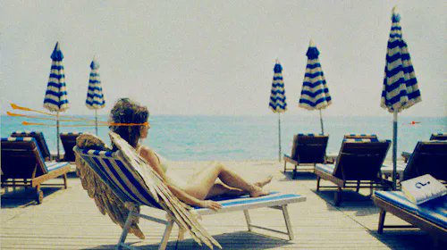 A figure lounges on a striped beach chair beneath blue-and-white umbrellas overlooking the sea, evoking a calm, contemplative seaside atmosphere. The painting, titled "SEA OF QUESTIONS," was sold by @rocketgirlart to @willcassidy for 0.2 ETH ($312.26) in the $RARE token.