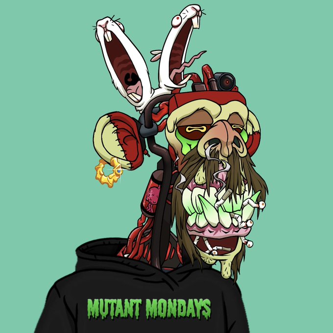 The image features a cartoon character wearing a black hoodie with the words "MUTANT MONTHS". The character has a face painted white, red, and green colors, giving them a unique appearance. They are holding a large pair of scissors in their hand, which is an unusual accessory for a cartoon character. The background color of the image is blue, providing a contrast to the colorful character's outfit.