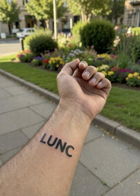 The image features a person with a tattoo of "LUNC" written on their arm, which says "LUNC" backwards. The person appears to be holding up their arm for the camera, possibly posing or showing off their tattoo. The caption at the bottom of the image reads "Someone Tattooed LUNC on his Arm stating that LUNC is going back to ATH". This suggests that the person with the tattoo might have a connection to athletic activities and is using their tattoo as a form of self-expression or a conversation starter related to sports.