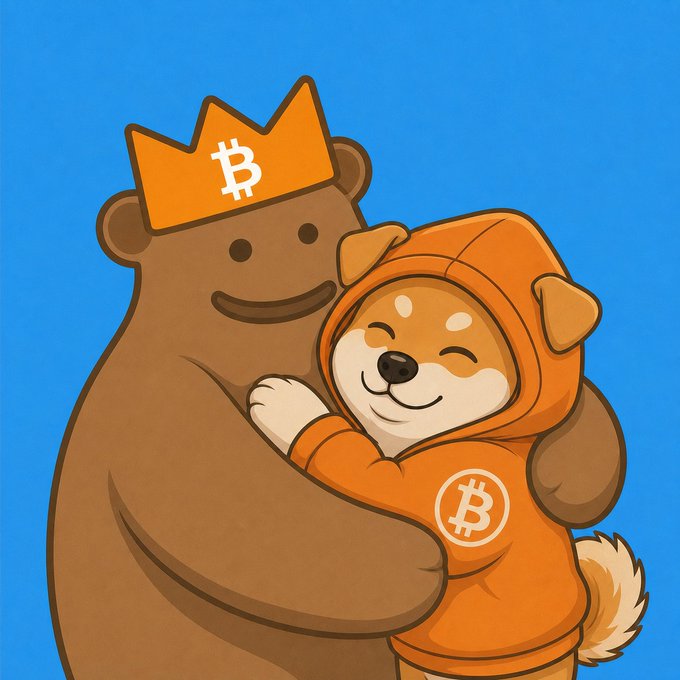 A cartoon illustration shows a large brown bear wearing a Bitcoin crown hugging a smiling Shiba Inu dog dressed in an orange Bitcoin hoodie against a blue background.