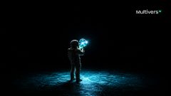 An astronaut stands in darkness holding a glowing blue light, with the "MultiversX" logo in the top right corner.
