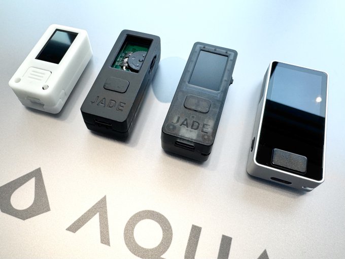 Four hardware cryptocurrency wallets of varying designs and sizes arranged on a surface above a Sui logo.