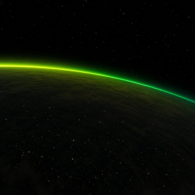 A glowing green aurora traces the curved horizon of Earth against a star-filled black sky, viewed from above as the planet completes its rotation. The image visually reinforces the caption's message of relentless, unbroken momentum—even as the Earth turns, the bright arc suggests an unceasing energy sweeping across the globe.