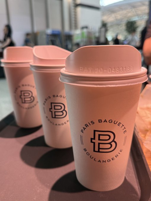 Three pink Paris Baguette Boulangerie cups with dome lids line up on a tray, with one cup showing 'PAT 20-0486156' on the lid.