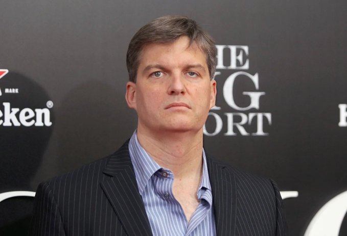 The image features a man dressed in a suit, standing against a black background with white text. The man appears to be looking off into the distance or at something out of frame. In the corner of the photo, there are two logos - one for "Hence" and another for "Big Short", which suggests that this could be related to an article about Bitcoin or cryptocurrency.