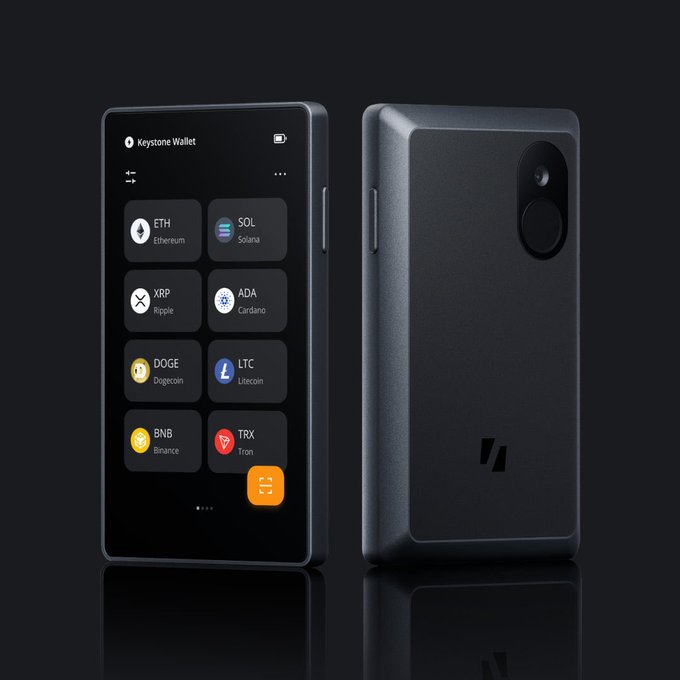 Two black hardware crypto wallets labeled "Keystone Wallet" displaying supported cryptocurrencies including ETH (Ethereum), SOL (Solana), XRP (Ripple), ADA (Cardano), DOGE (Dogecoin), LTC (Litecoin), BNB (Binance), and TRX (Tron).
