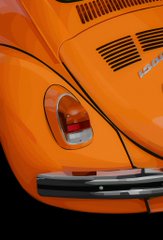 A close-up image of the rear section of an orange classic car, showing the tail light and part of the bumper.