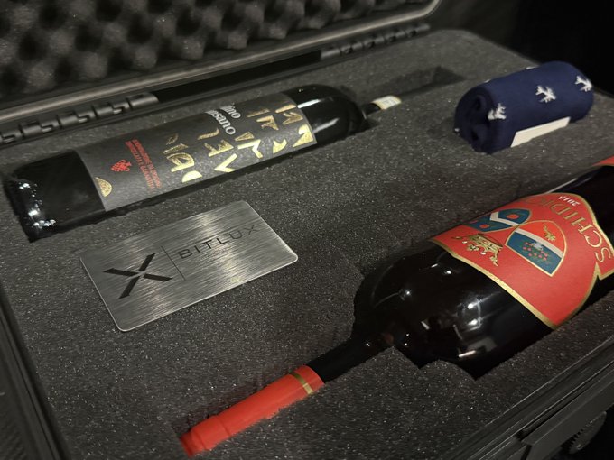 A black protective case holds a Bitlux-branded bottle of wine and another bottle, along with a rolled navy cloth napkin.
