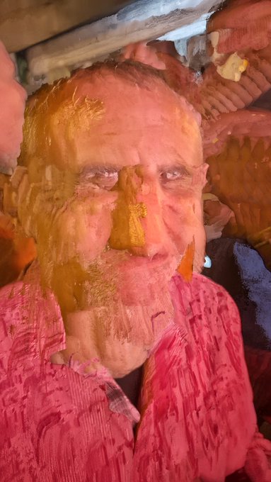 A heavily stylized, painterly close-up portrait of an older man with a beard and glasses, wearing a pink shirt.