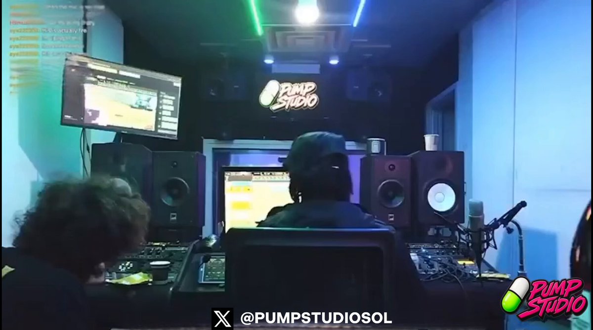 The image shows two people sitting at a desk with headphones, likely working on music production or recording. The background features a monitor displaying a video feed of another person's face, possibly indicating that they are streaming their work online. The image also includes text elements such as "Studio is LIVE" and "The first music production podcast show built for the culture & streaming live on @Pumpfun We have a long-term vision & we really want to grow $Studio Real artists. Real energy. Real utility."