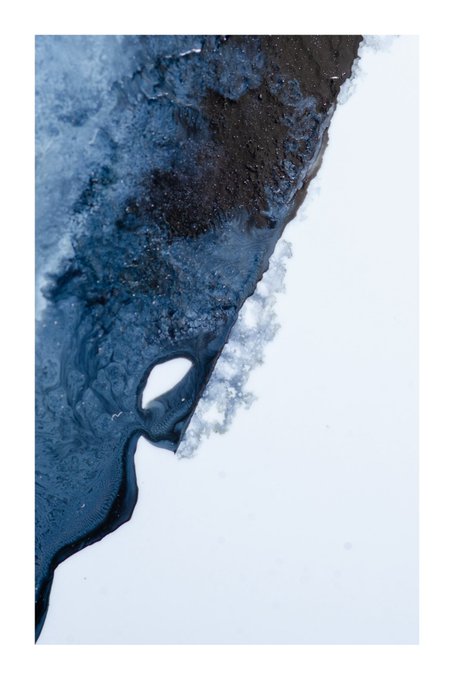 An aerial or satellite view showing a dark blue waterway or estuary meeting white snow or ice, with a distinctive teardrop-shaped island visible.