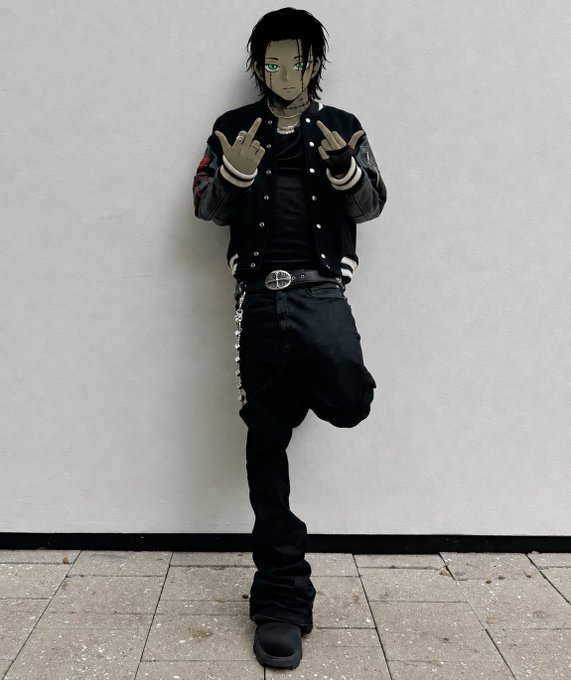 A person wearing a black and white varsity jacket, black jeans with a chain, and black boots poses against a white wall while making middle finger gestures with both hands.