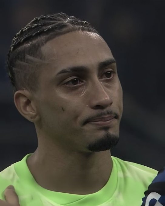 A close-up photograph shows a male athlete with braided hair and a goatee, appearing emotional with a tear on his face, wearing a neon yellow shirt.