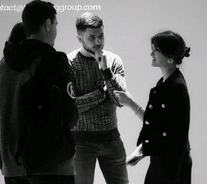 A black and white photo of three people conversing, with an email address 'contact@...group.com' visible at the top left.
