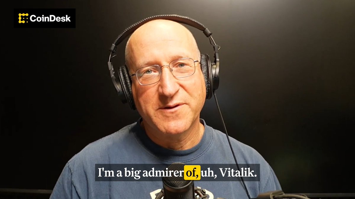 A bald man with glasses and headphones, identified by the context as Eli Ben Sasson, speaks into a microphone in a dark studio setting during a CoinDesk interview, with the subtitle "I'm a big admirer of, uh, Vitalik" capturing his praise of Vitalik Buterin's "very good" and "very ambitious" Ethereum roadmap.