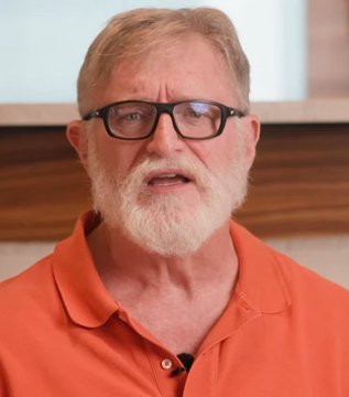 A close-up of an older man with a white beard wearing glasses and an orange polo shirt.