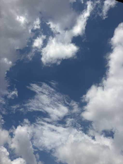 A photograph of a bright blue sky scattered with fluffy white clouds.