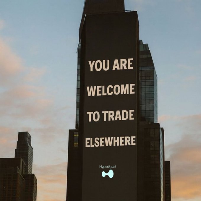 A tall skyscraper displays large illuminated text reading "YOU ARE WELCOME TO TRADE ELSEWHERE" with a "Hyperliquid" logo and bowtie icon below against a dusk sky.