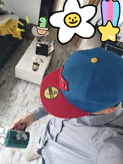 A photo of a child wearing a blue and red baseball cap holding a mug, with playful hand-drawn doodles of a flower, cactus, star, and exclamation marks overlaid on the image.
