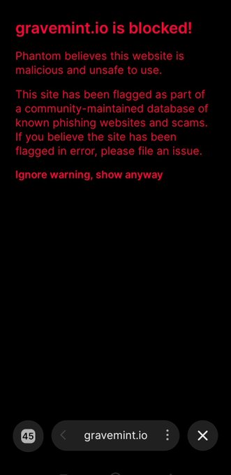 The image displays a Phantom wallet warning screen showing that "gravemint.io is blocked" because Phantom believes the website is malicious and has flagged it as part of a community-maintained database of known phishing websites and scams. This screenshot relates to the post criticizing Phantom's vouching/whitelist process for blocking websites, highlighting that despite claims of being whitelisted, the site is still being flagged as a phishing scam, with an option to "Ignore warning, show anyway."