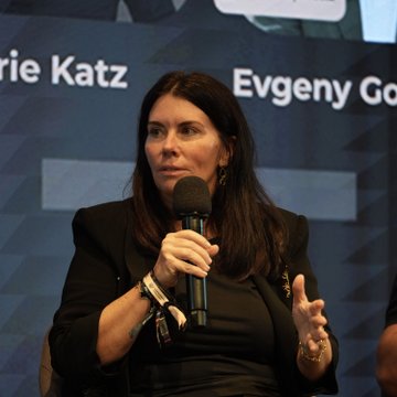 Laurie Katz, identified by the on-screen text, speaks into a microphone while seated on a panel at LONGITUDE Singapore, with the accompanying post noting her bullish remarks on how institutional players like banks, family offices, and pension funds are exploring crypto to potentially drive broader adoption.