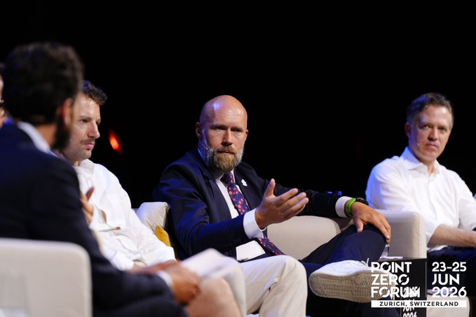 A panel of four men sits on stage at the Point Zero Forum 2026 in Zurich, Switzerland (June 23-25), with the bearded speaker in the center actively gesturing as he discusses programmable money, digital identity, and AI trust—topics highlighted in the accompanying recap post.