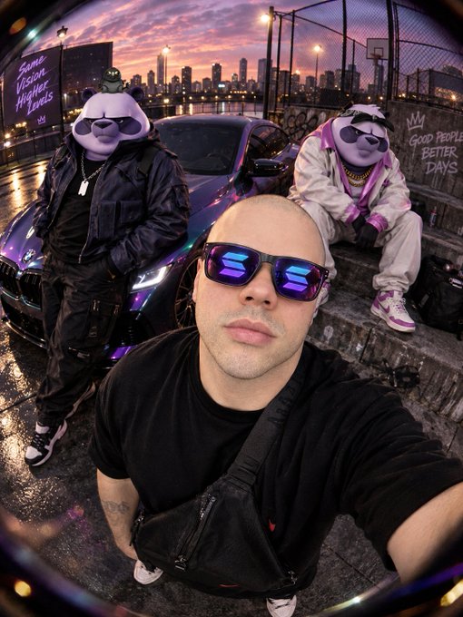 A fisheye lens selfie shows a man in sunglasses in the foreground, with two people wearing bear and panda masks behind him near a sports car at dusk with a city skyline in the background.