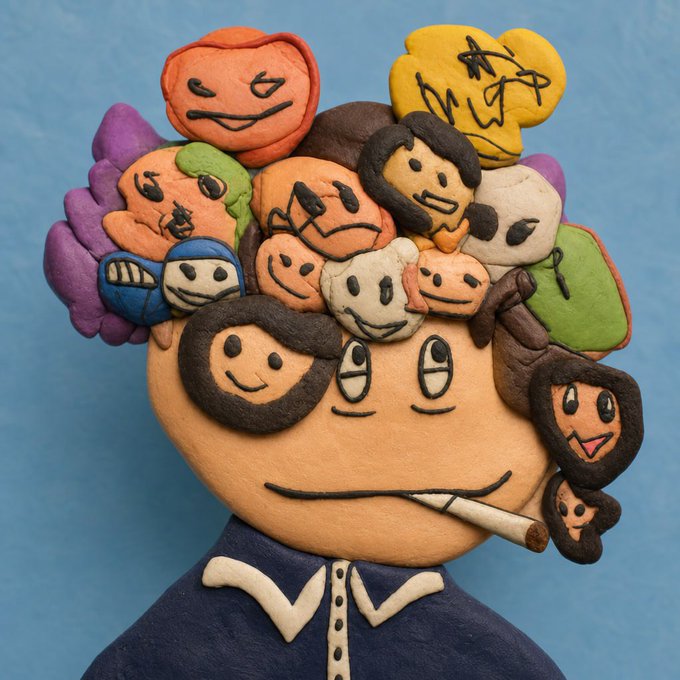 A whimsical clay sculpture of a figure with a large round head, multiple colorful smaller faces with various expressions emerging from its hair, and a cigarette dangling from its mouth.