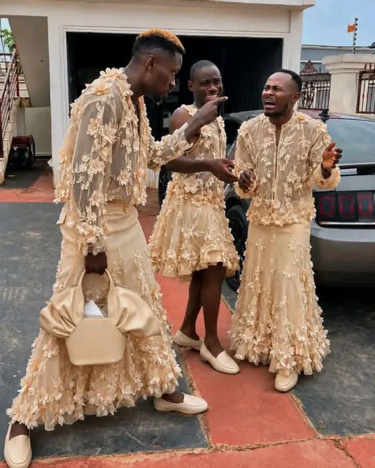 Three people pose playfully in matching beige floral lace outfits in front of a luxury home and car, with the original post's comment about "Shameless Marketing" likely referring to their coordinated, eye-catching attire designed to draw attention.