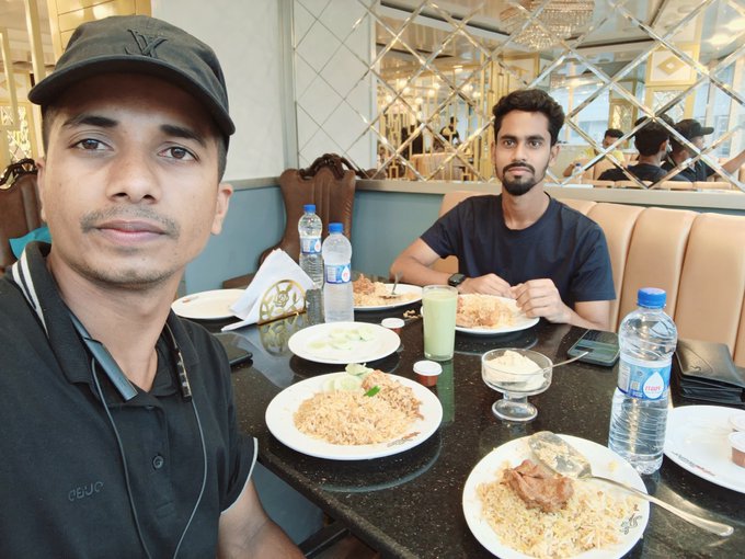Two men enjoy a relaxed breakfast of rice and curry at a restaurant table set with bottled water and green drinks, paired with the caption emphasizing that "the best alpha is simply starting the day right."